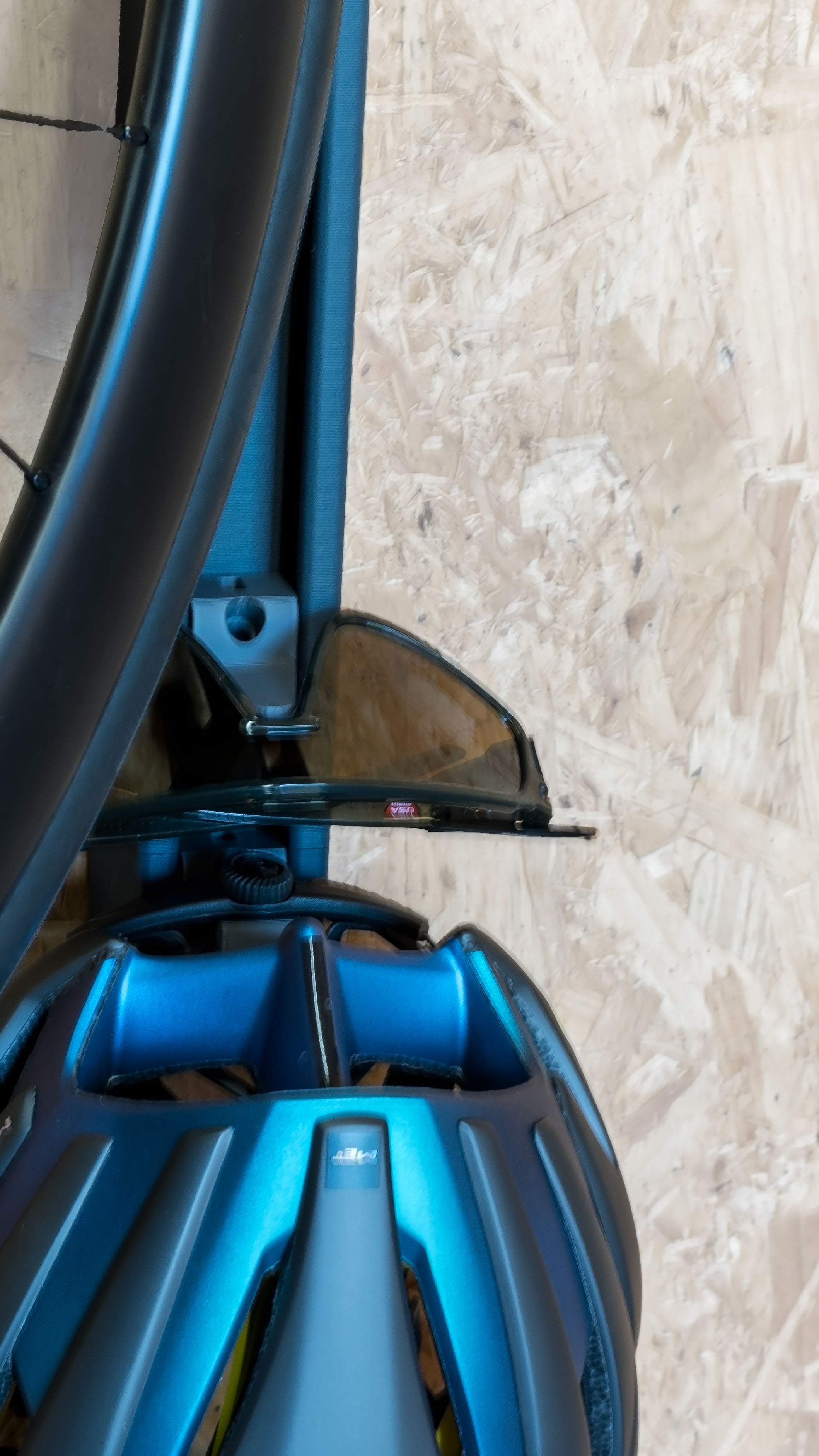 A zoomed in photo of a helmet and sunglasses stored with a road bike using a vertical storage system.