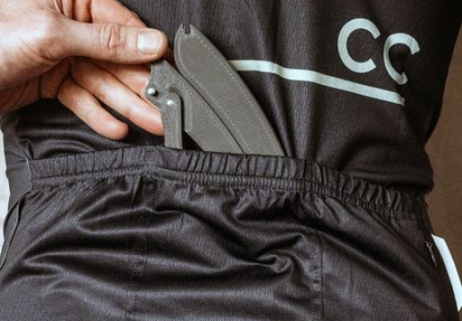 Image shows a rider placing the folded PLAced modular tyre lever the tirer into his back jersey pcoket