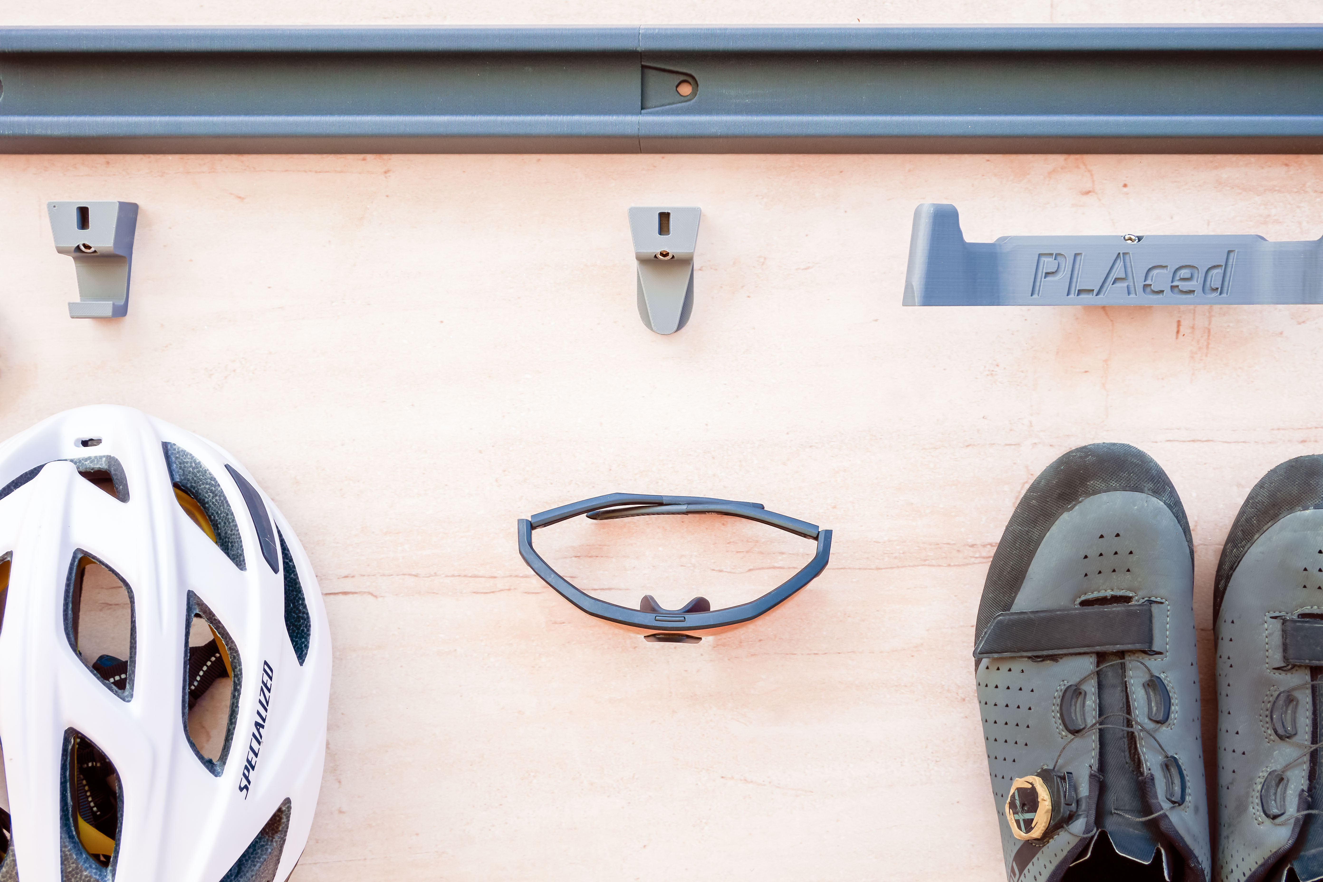 Cycling Kit: White Helmet, Glasses and shoes layout out underneath The Verticale upright rail system ready to be installed on the wall. Below the rail are the hooks ready for installation
